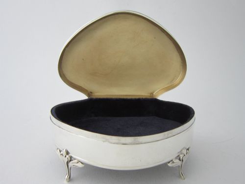 fig 1. A kidney-shaped antique sterling silver trinket box with a beaded edge hinged lid standing on small decorative feet.