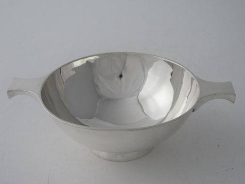 fig 1. A solid sterling silver Scottish quaich featuring a shallow circular bowl, two flat lateral handles, and a low raised foot.