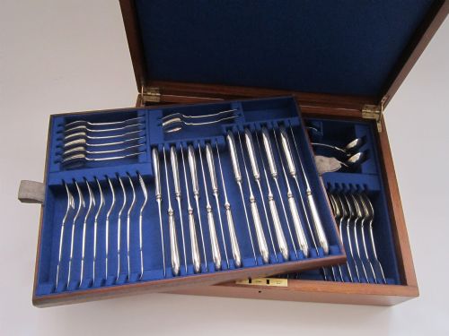 fig 1. An open fitted wooden canteen displaying a multi-piece sterling silver cutlery set in fiddle pattern on blue velvet lining.
