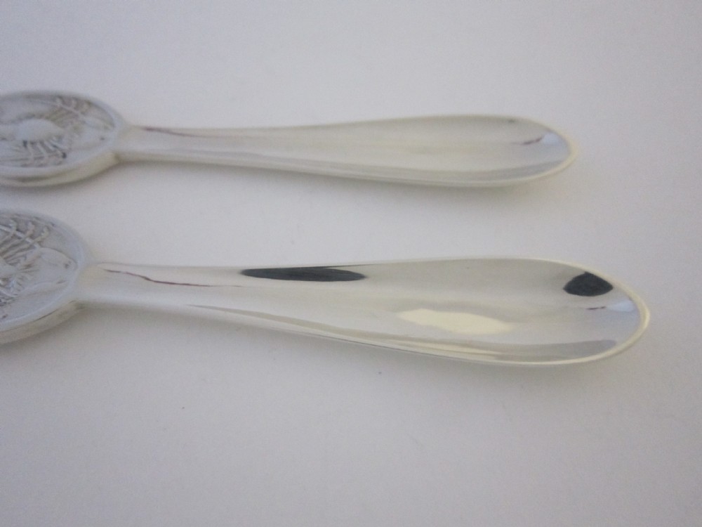 A pair of sterling silver lobster picks with embossed central medallions displayed inside an open black velvet-lined box. View VIII