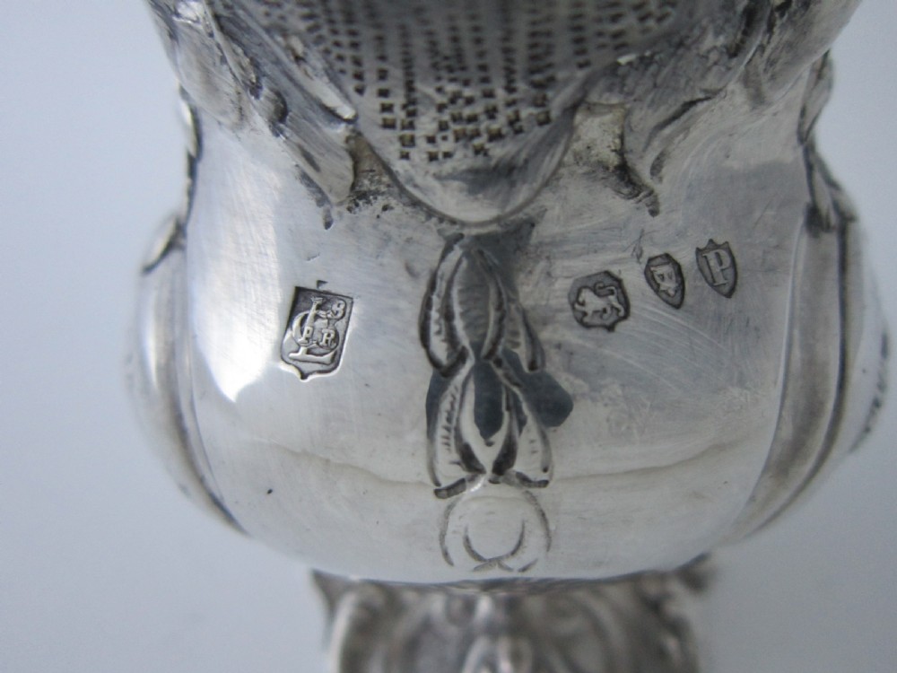 Victorian sterling silver cream jug with detailed repousse pastoral scenes, a high scroll handle, a gilt interior, and a cast foot. View VIII