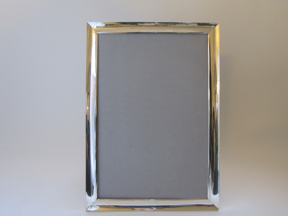 A large rectangular sterling silver picture frame with a simple moulded border and a grey fabric insert in a landscape alignment. View IX
