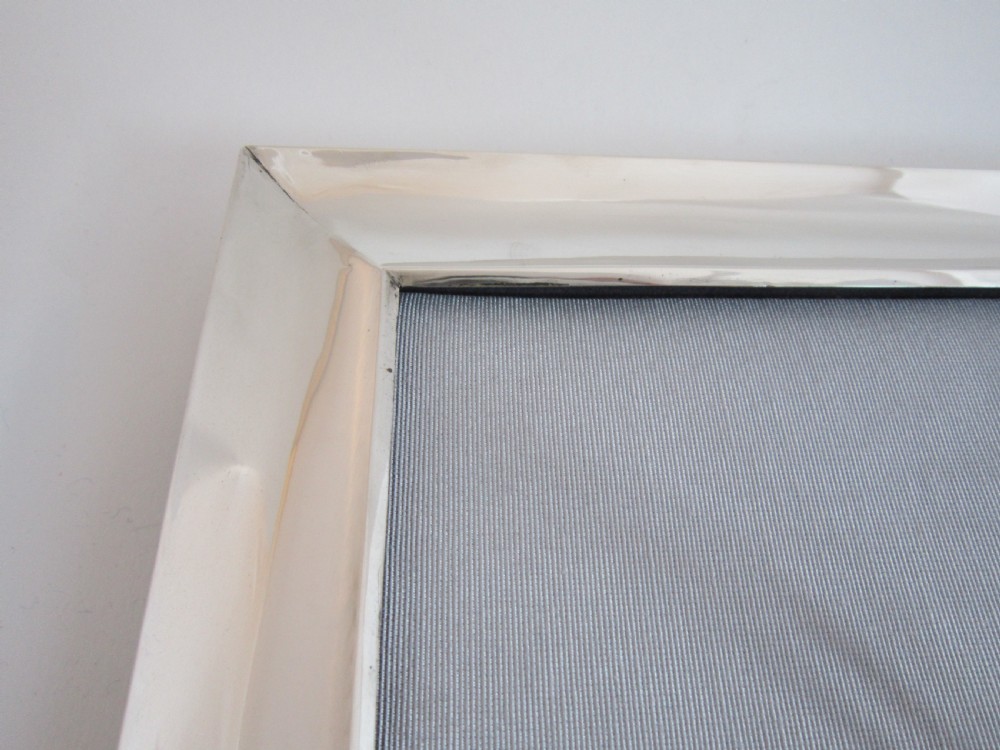 A large rectangular sterling silver picture frame with a simple moulded border and a grey fabric insert in a landscape alignment. View XIII
