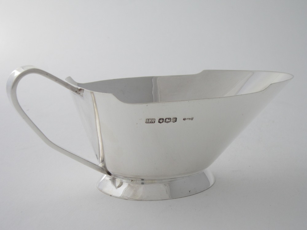 A polished sterling silver Art Deco sauce boat with clean geometric lines, an integrated pouring spout, a loop handle, and a raised oval foot. View II