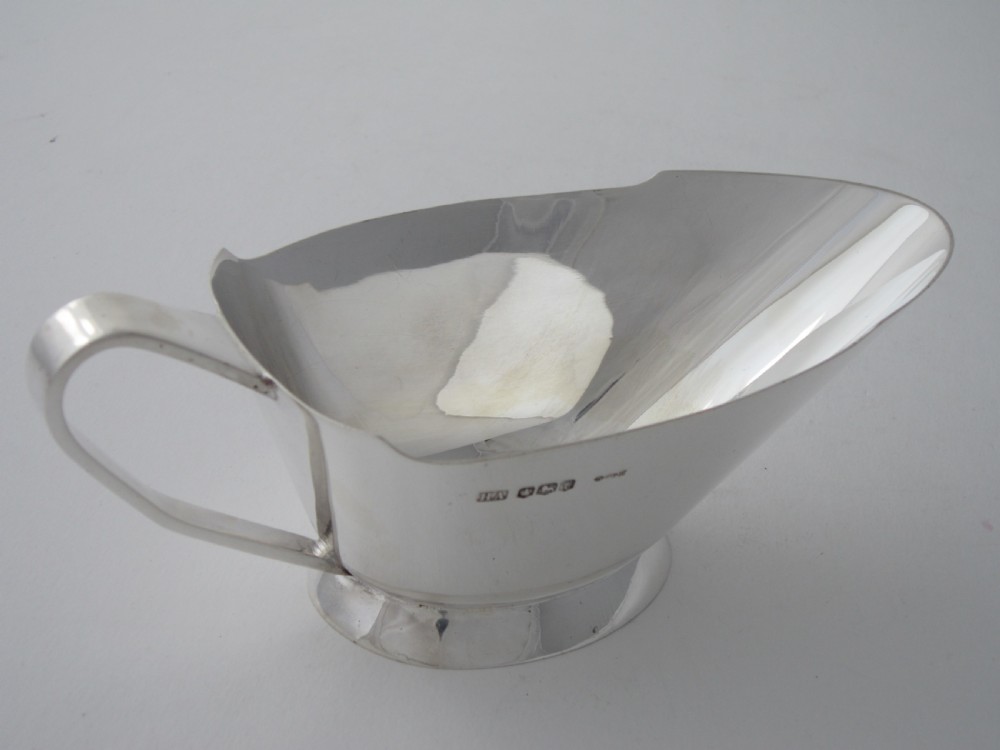A polished sterling silver Art Deco sauce boat with clean geometric lines, an integrated pouring spout, a loop handle, and a raised oval foot. View III