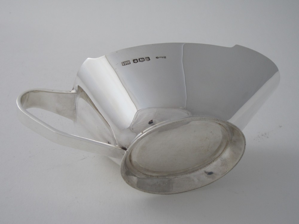 A polished sterling silver Art Deco sauce boat with clean geometric lines, an integrated pouring spout, a loop handle, and a raised oval foot. View IV