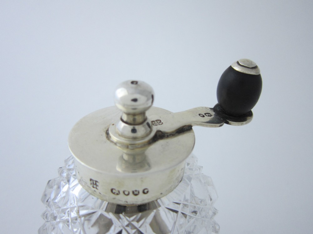 A Victorian sterling silver and cut glass pepper mill with a hand crank handle and hallmarked silver base. View II