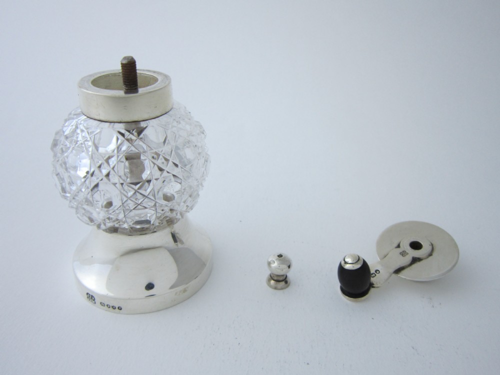 A Victorian sterling silver and cut glass pepper mill with a hand crank handle and hallmarked silver base. View VI