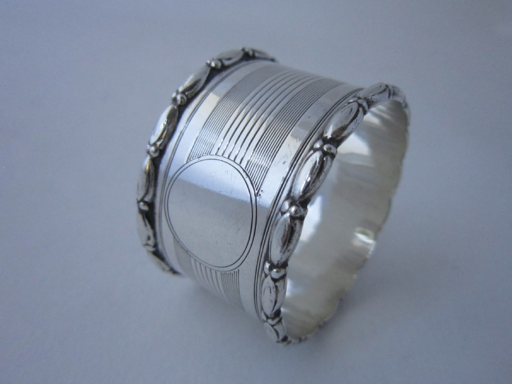 A George V sterling silver napkin ring featuring engine-turned line engraving, beaded borders, and a blank circular central cartouche. View II