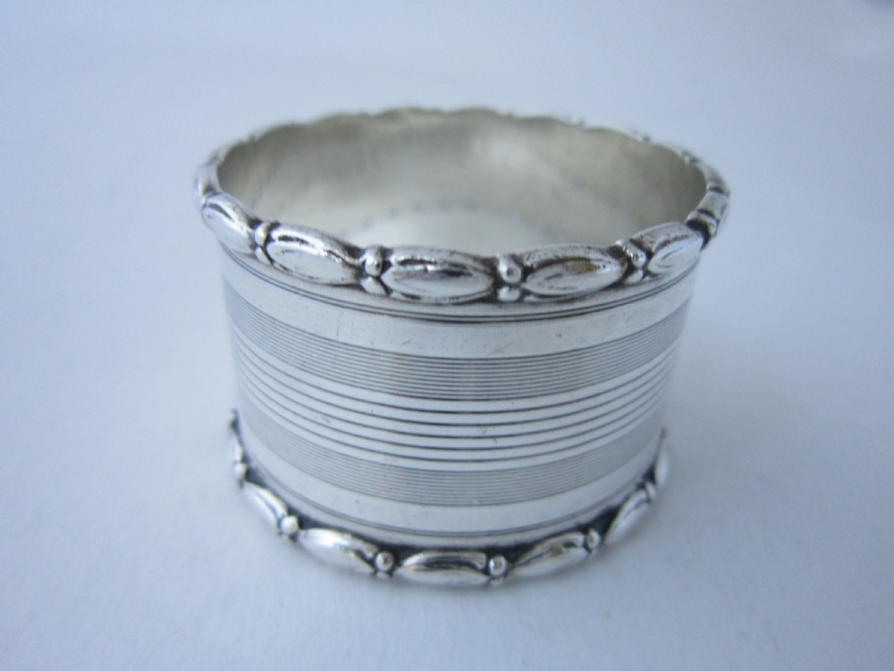 A George V sterling silver napkin ring featuring engine-turned line engraving, beaded borders, and a blank circular central cartouche. View III