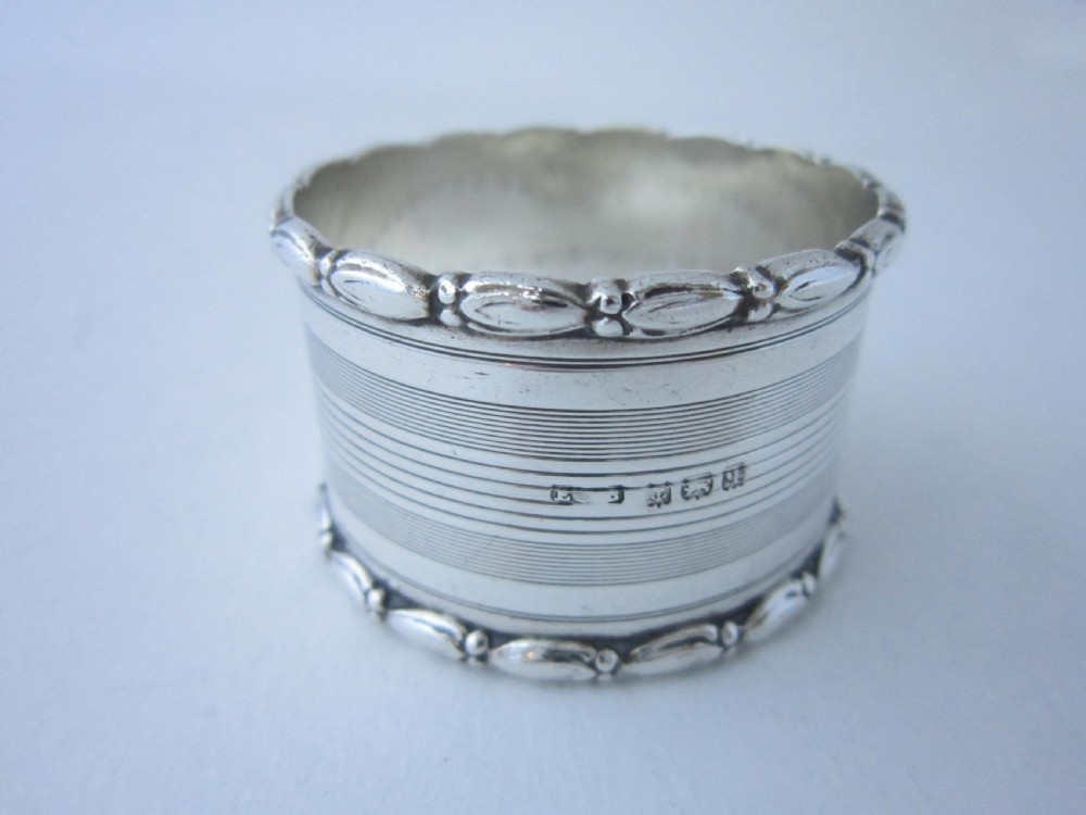 A George V sterling silver napkin ring featuring engine-turned line engraving, beaded borders, and a blank circular central cartouche. View V