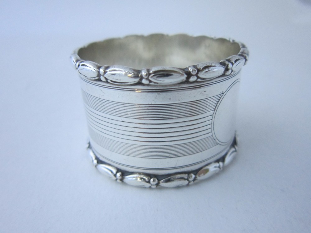 A George V sterling silver napkin ring featuring engine-turned line engraving, beaded borders, and a blank circular central cartouche. View VI