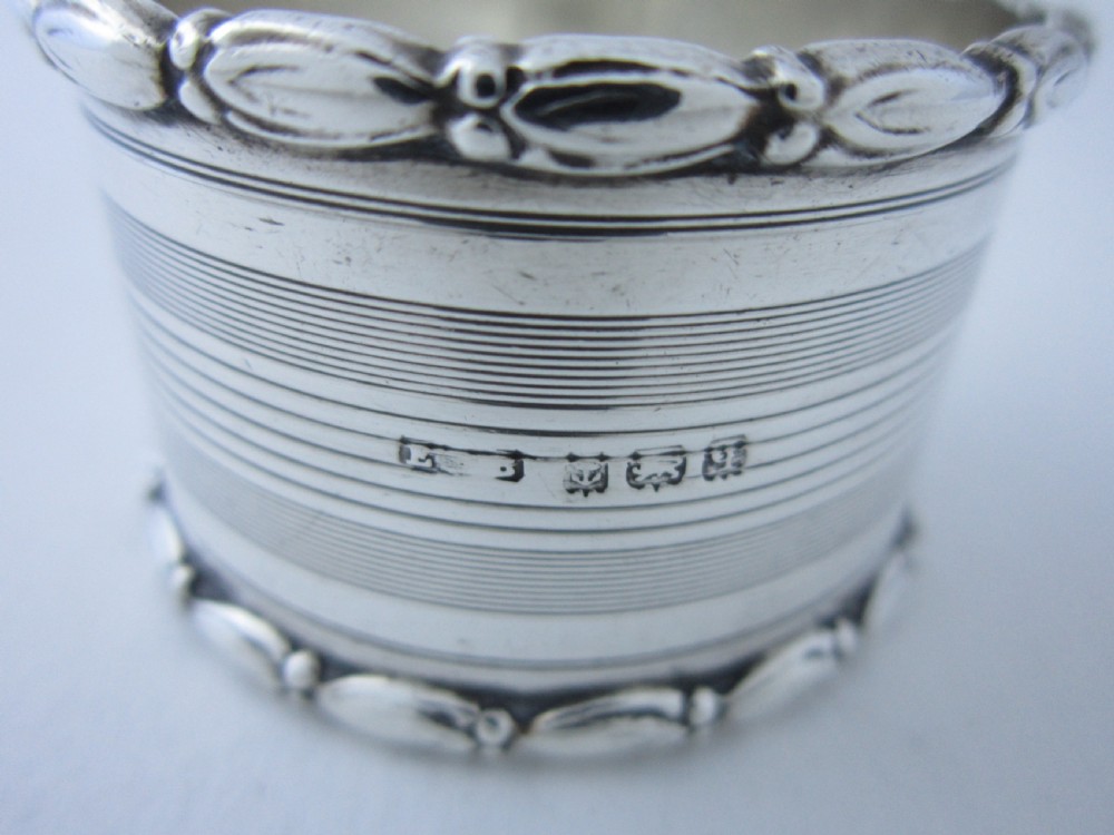 A George V sterling silver napkin ring featuring engine-turned line engraving, beaded borders, and a blank circular central cartouche. View VII
