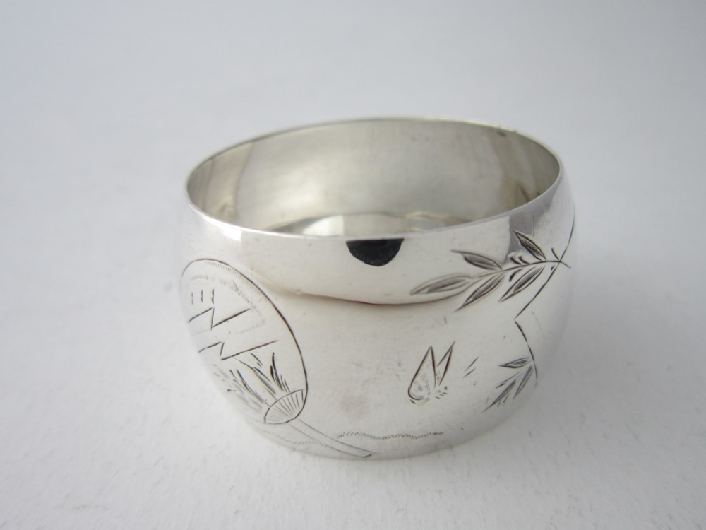 An antique late Victorian sterling silver napkin ring featuring hand-engraved foliate motifs and a polished finish. View II