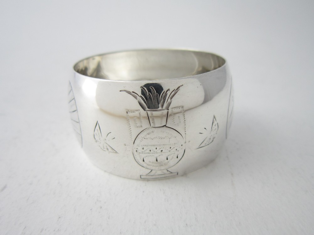 An antique late Victorian sterling silver napkin ring featuring hand-engraved foliate motifs and a polished finish. View V