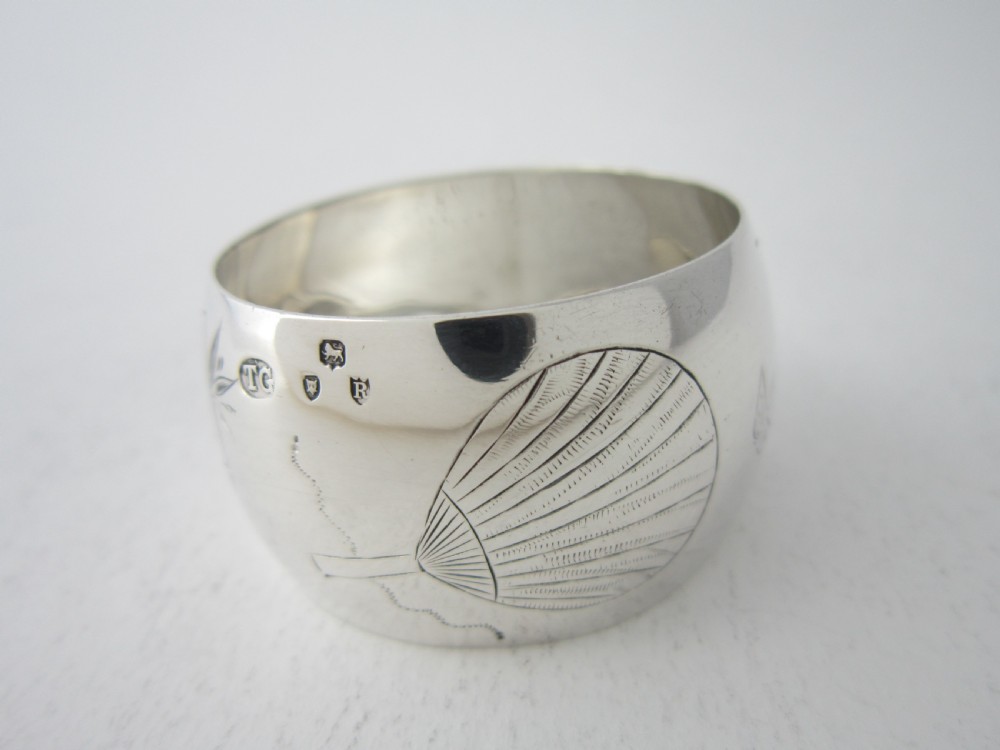 An antique late Victorian sterling silver napkin ring featuring hand-engraved foliate motifs and a polished finish. View VI