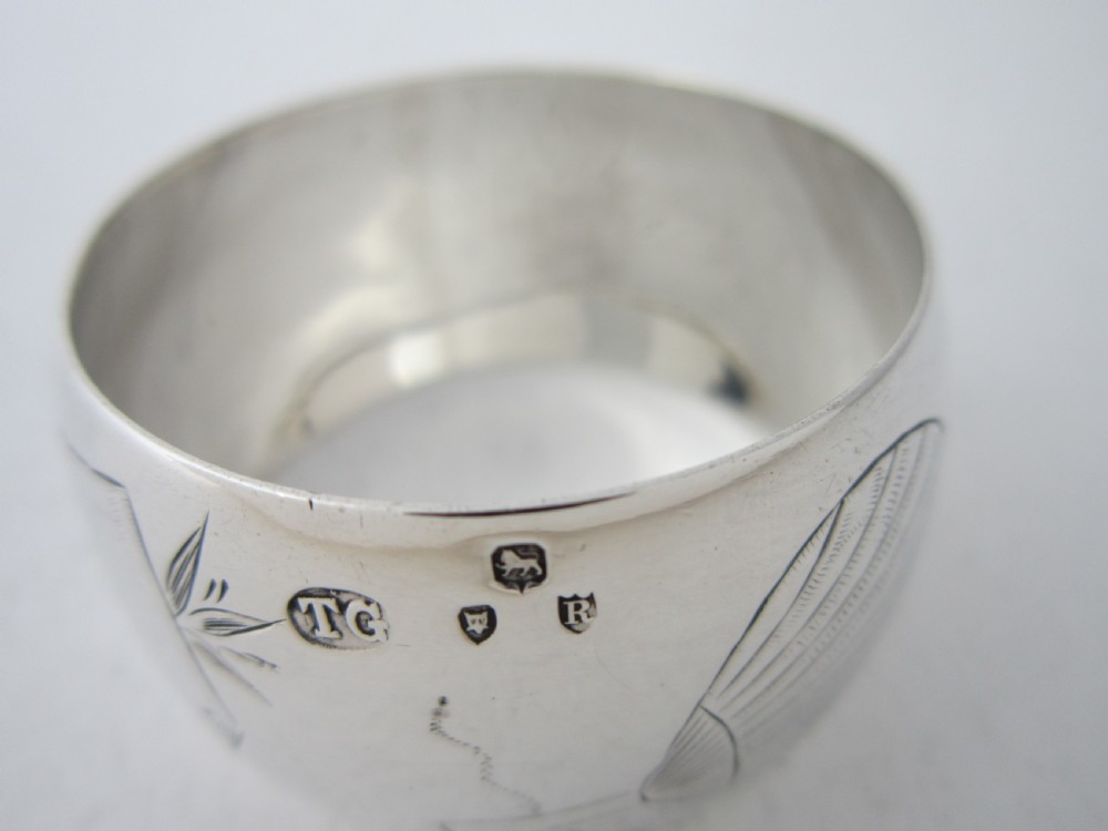 An antique late Victorian sterling silver napkin ring featuring hand-engraved foliate motifs and a polished finish. View VII