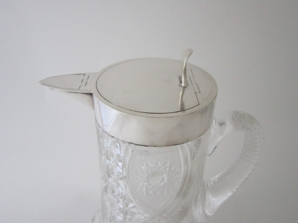 An Edwardian silver-mounted clear cut glass jug featuring geometric diamond carving, a notched glass handle, and a polished sterling silver spout. View II