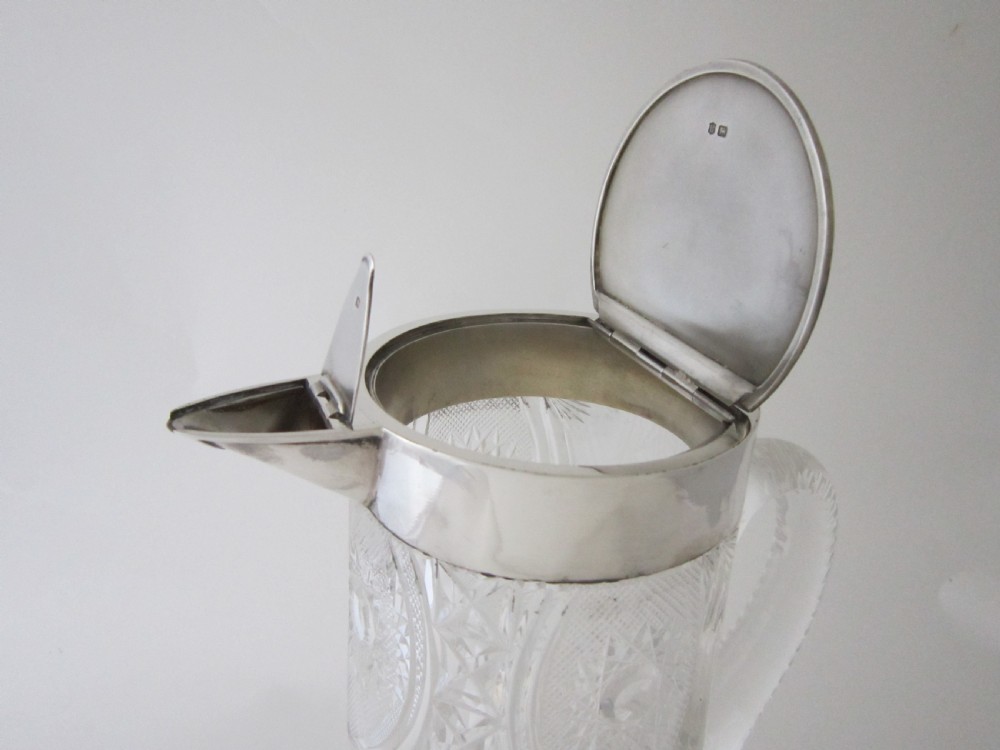 An Edwardian silver-mounted clear cut glass jug featuring geometric diamond carving, a notched glass handle, and a polished sterling silver spout. View III