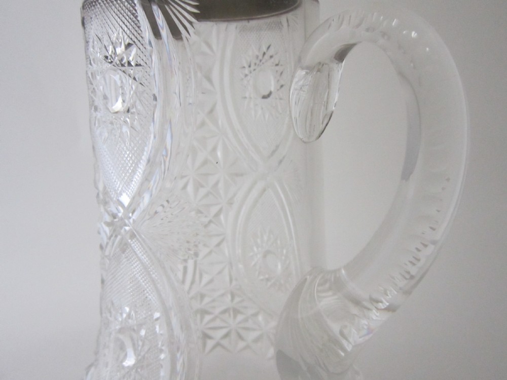An Edwardian silver-mounted clear cut glass jug featuring geometric diamond carving, a notched glass handle, and a polished sterling silver spout. View IV