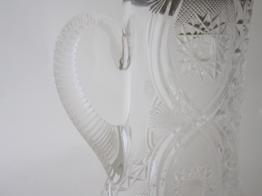 An Edwardian silver-mounted clear cut glass jug featuring geometric diamond carving, a notched glass handle, and a polished sterling silver spout. View VI