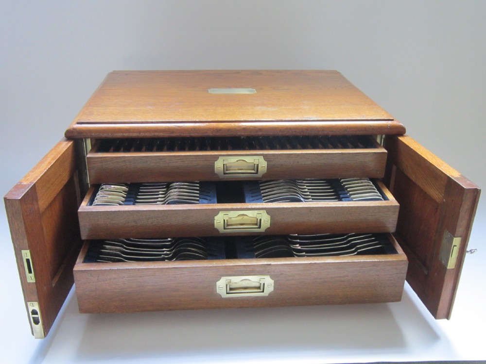 A Victorian fitted oak canteen chest with brass campaign handles open to reveal three drawers containing sterling silver fiddle pattern cutlery.