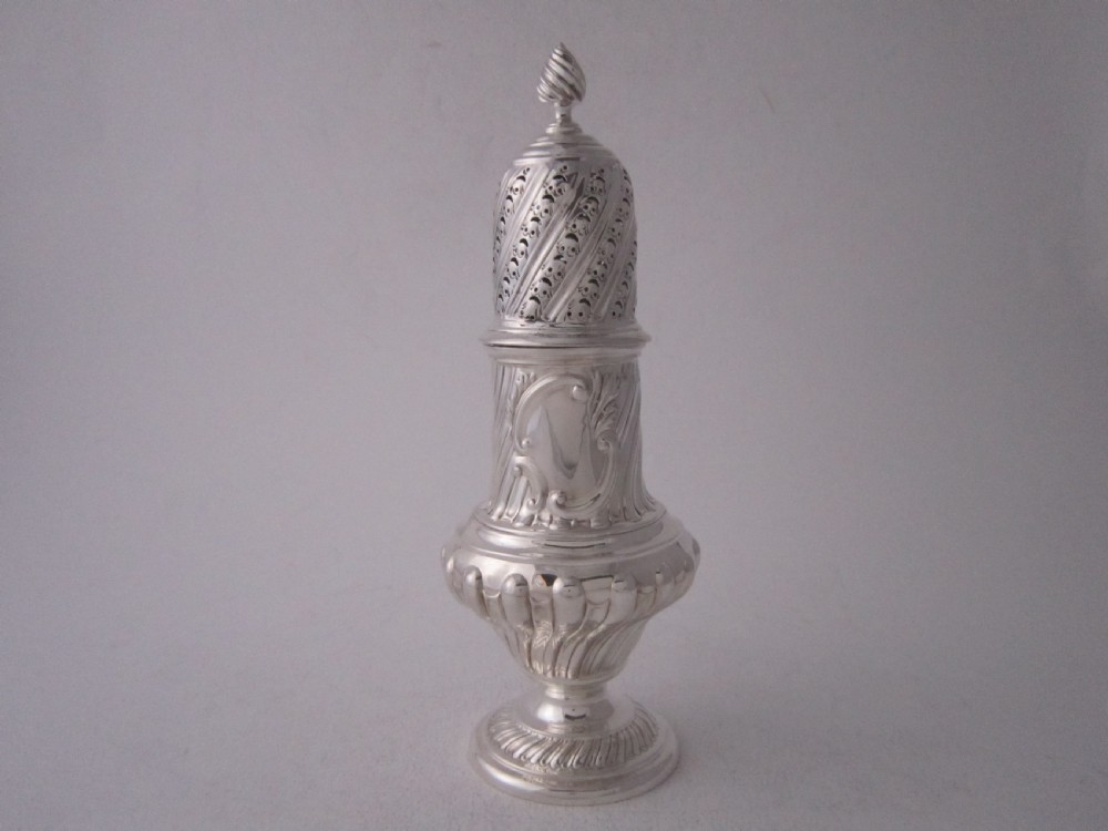 A Victorian sterling silver sugar caster with a spiralled finial, a hand-pierced cap, and a decorated baluster-shaped body.