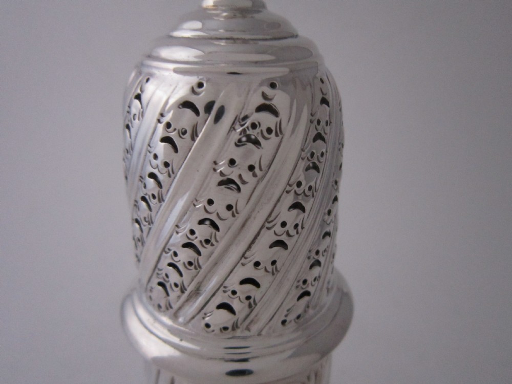 A Victorian sterling silver sugar caster with a spiralled finial, a hand-pierced cap, and a decorated baluster-shaped body. View V