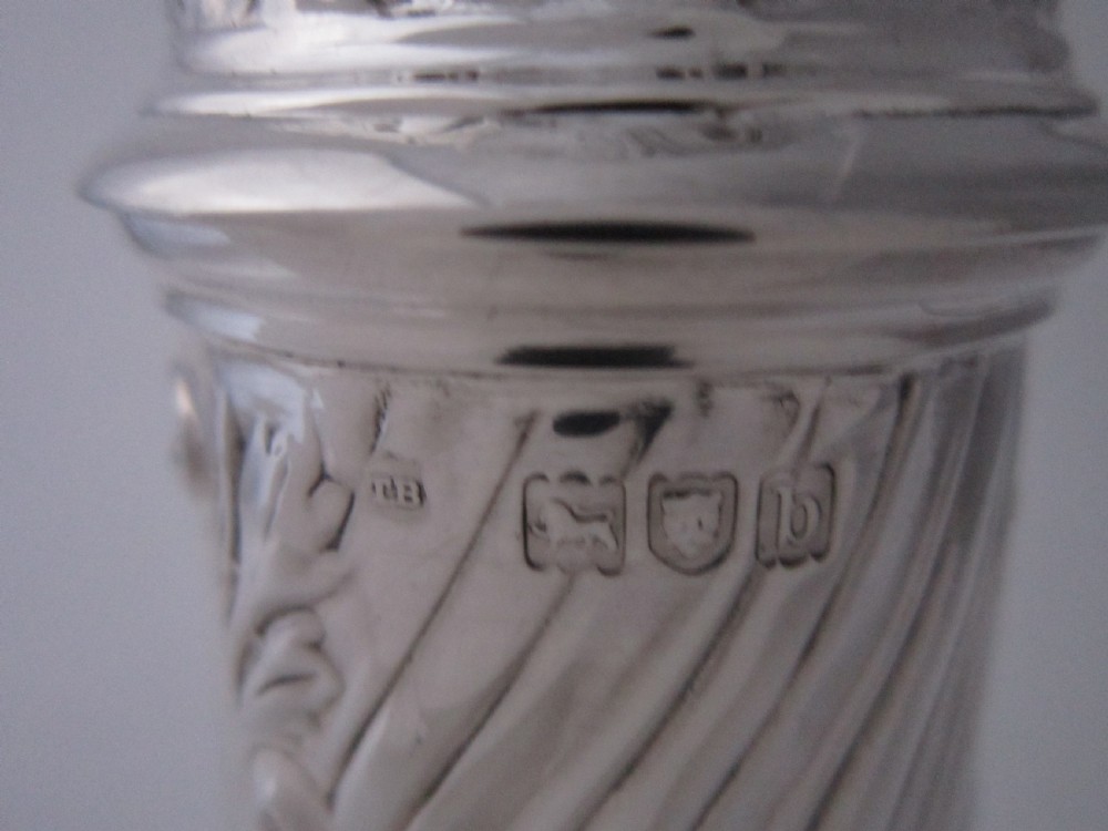 A Victorian sterling silver sugar caster with a spiralled finial, a hand-pierced cap, and a decorated baluster-shaped body. View VIII