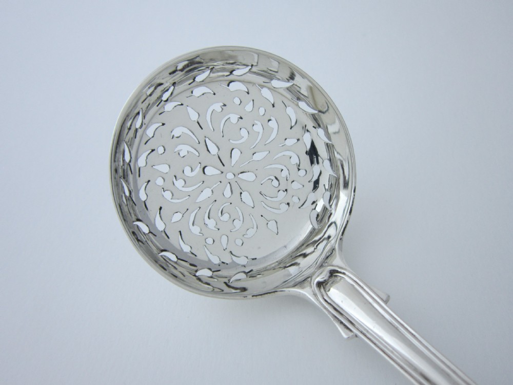 A Victorian sterling silver sifter spoon featuring a pierced scrolled bowl design and a Fiddle and Thread pattern handle. View II