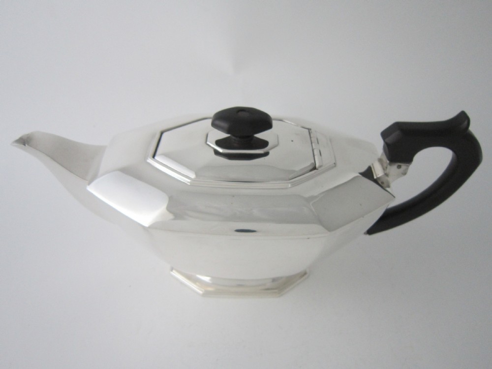 An octagonal sterling silver teapot featuring a carved black wooden handle and matching black lid finial, resting on a faceted pedestal base. View II