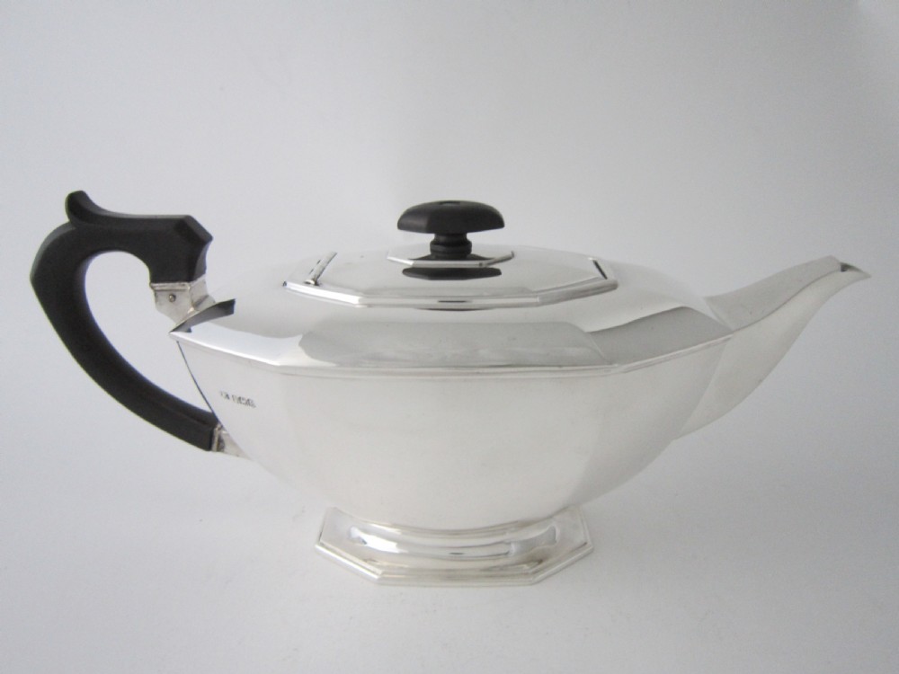 An octagonal sterling silver teapot featuring a carved black wooden handle and matching black lid finial, resting on a faceted pedestal base. View III