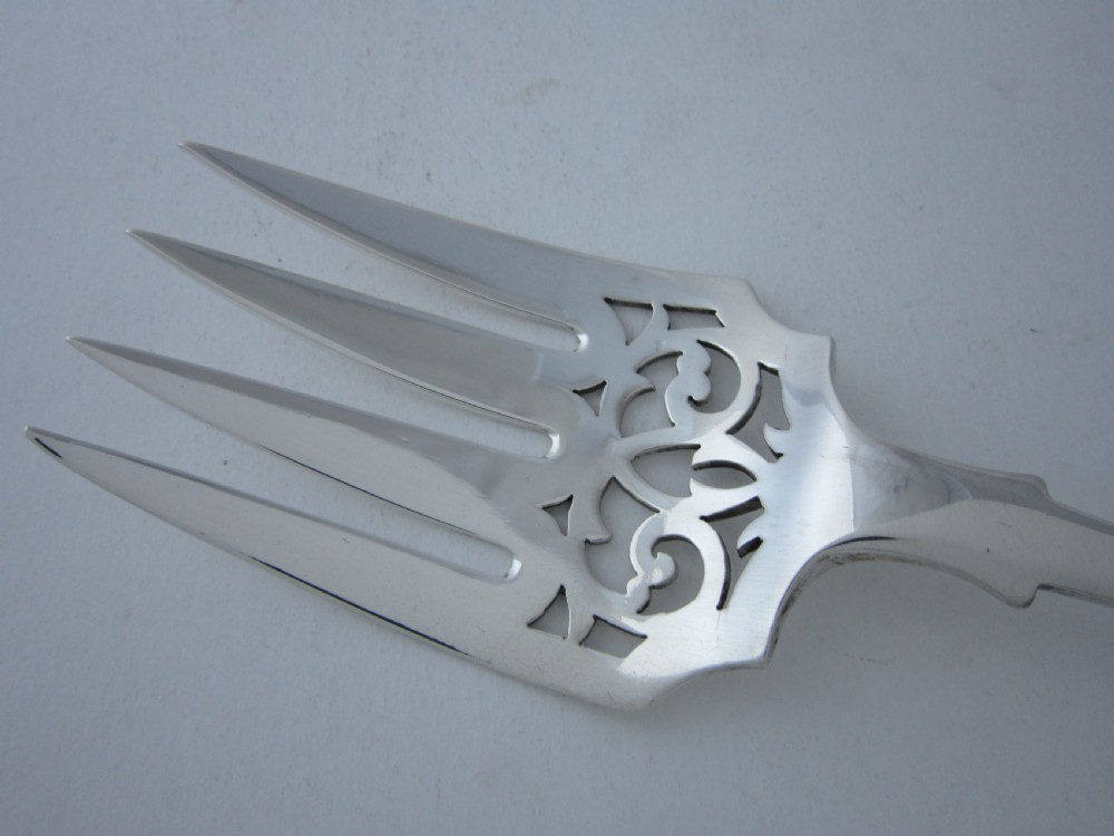 A pair of Victorian sterling silver fish servers featuring a pierced scrollwork knife blade and a four-tine fork with fiddle pattern handles. View V
