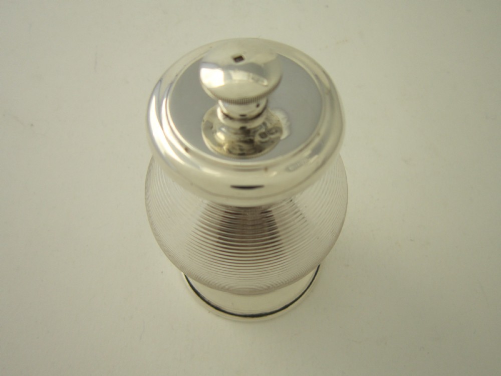 An Edwardian sterling silver and ribbed clear glass pepper grinder with hallmarked silver mounts on the top and base. View II
