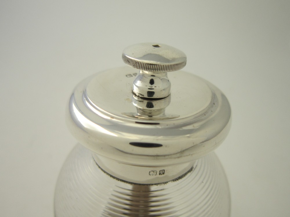 An Edwardian sterling silver and ribbed clear glass pepper grinder with hallmarked silver mounts on the top and base. View III