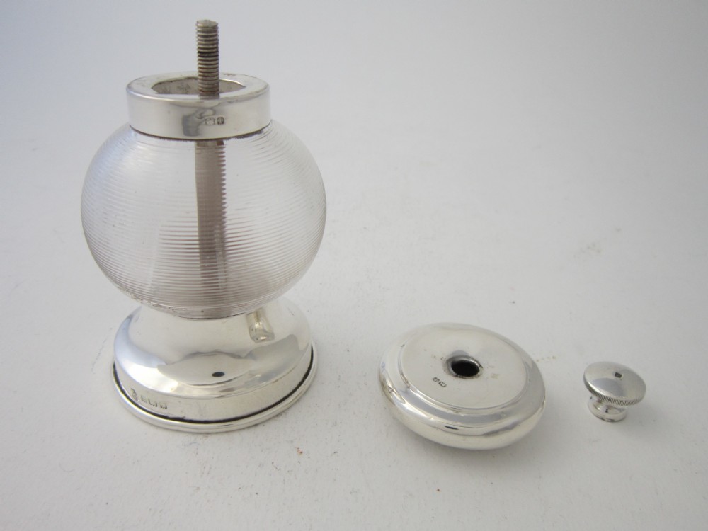 An Edwardian sterling silver and ribbed clear glass pepper grinder with hallmarked silver mounts on the top and base. View V