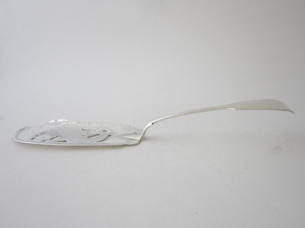An Irish George IV sterling silver fish slice with a pierced fish motif on the blade and a fiddle pattern handle. View IV