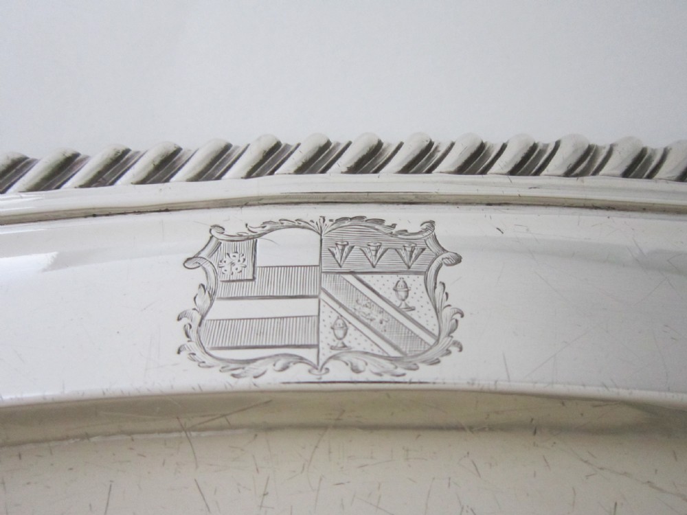 An oval William IV sterling silver meat platter featuring a gadrooned rim and an engraved heraldic coat of arms. View II
