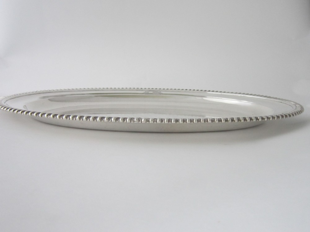 An oval William IV sterling silver meat platter featuring a gadrooned rim and an engraved heraldic coat of arms. View III