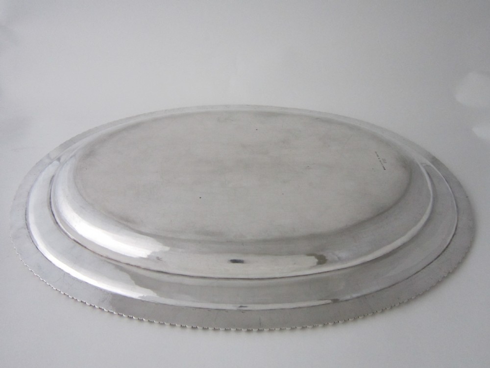 An oval William IV sterling silver meat platter featuring a gadrooned rim and an engraved heraldic coat of arms. View IV