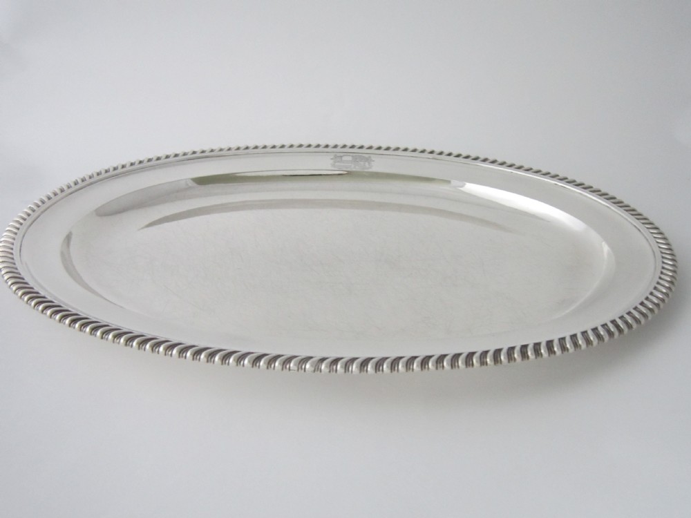 An oval William IV sterling silver meat platter featuring a gadrooned rim and an engraved heraldic coat of arms. View V