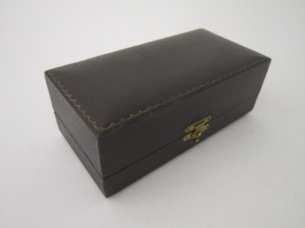 A pair of faceted sterling silver Art Deco napkin rings with subtle engine-turned patterning, presented in a fitted black display box with a cream satin lining. View II