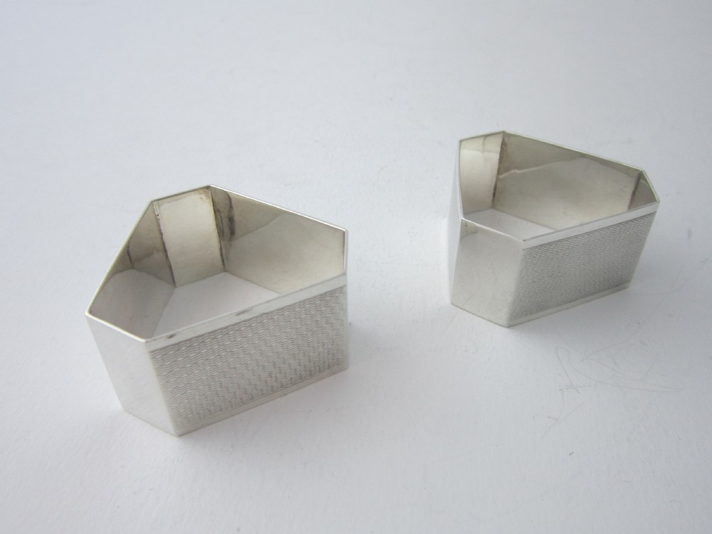 A pair of faceted sterling silver Art Deco napkin rings with subtle engine-turned patterning, presented in a fitted black display box with a cream satin lining. View III