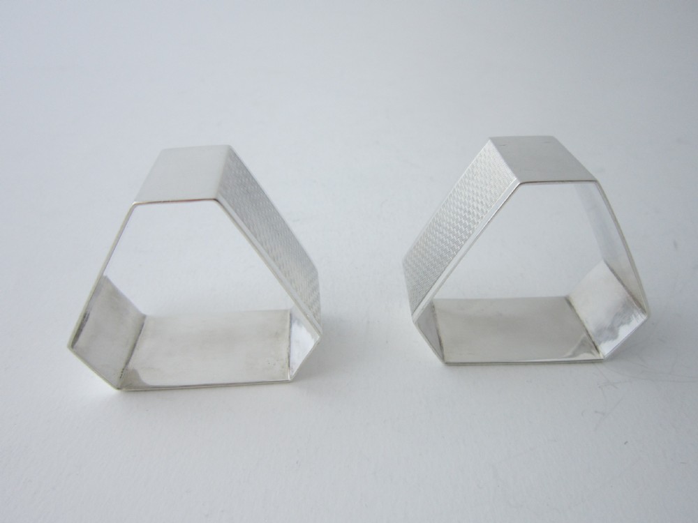 A pair of faceted sterling silver Art Deco napkin rings with subtle engine-turned patterning, presented in a fitted black display box with a cream satin lining. View IV