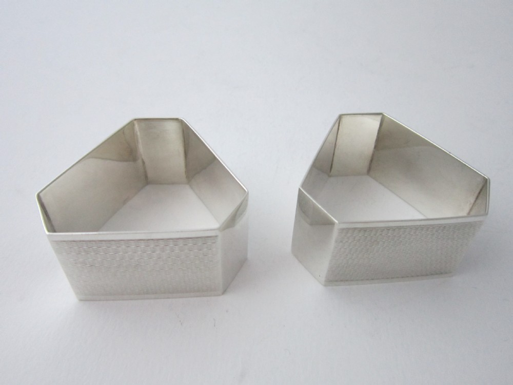 A pair of faceted sterling silver Art Deco napkin rings with subtle engine-turned patterning, presented in a fitted black display box with a cream satin lining. View V
