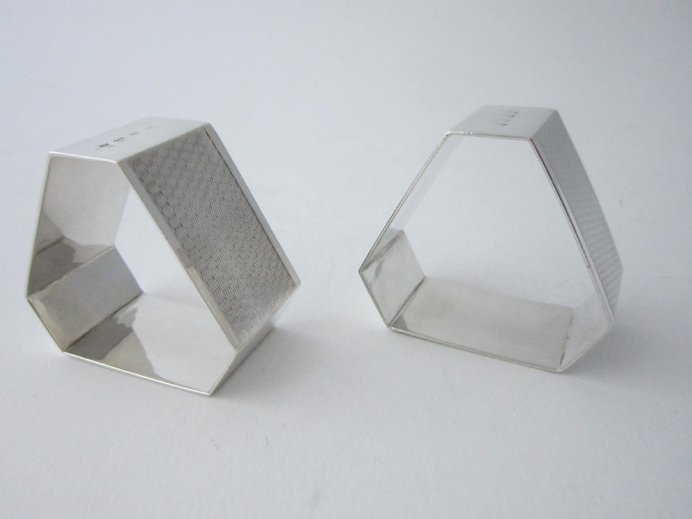 A pair of faceted sterling silver Art Deco napkin rings with subtle engine-turned patterning, presented in a fitted black display box with a cream satin lining. View VI