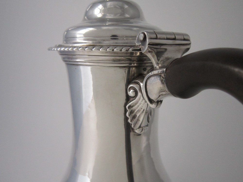 A George III sterling silver coffee pot with a baluster body, carved wooden handle, gadrooned base border, and an ornate cast spout. View VII