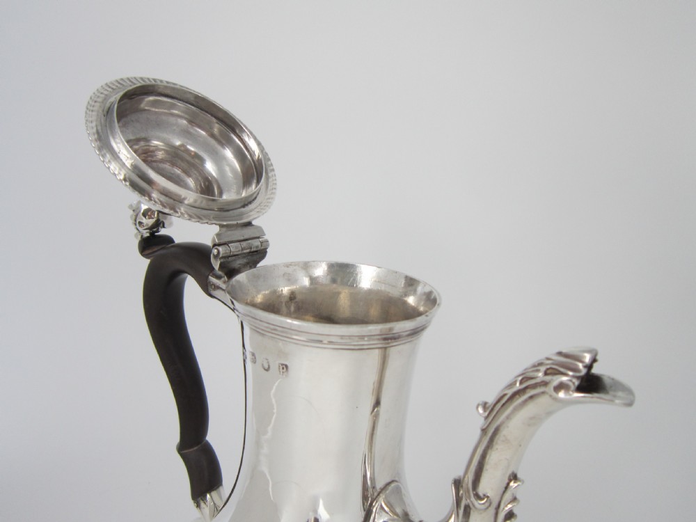 A George III sterling silver coffee pot with a baluster body, carved wooden handle, gadrooned base border, and an ornate cast spout. View IX