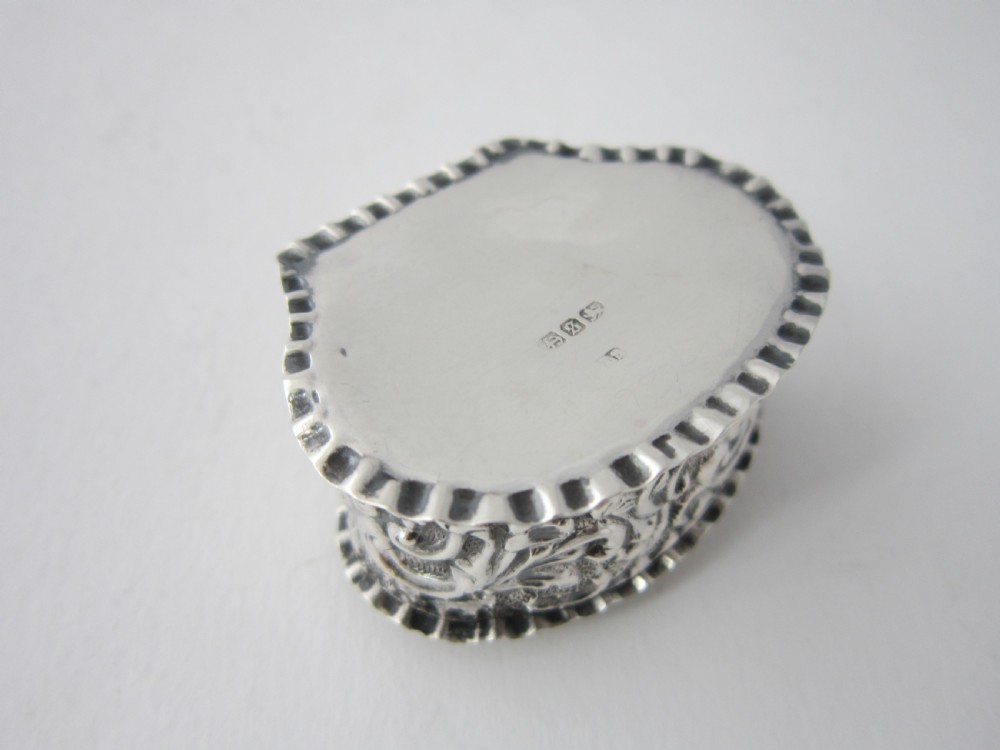 A small Victorian sterling silver pill box decorated with embossed scrollwork and a crimped frilled rim. View VI