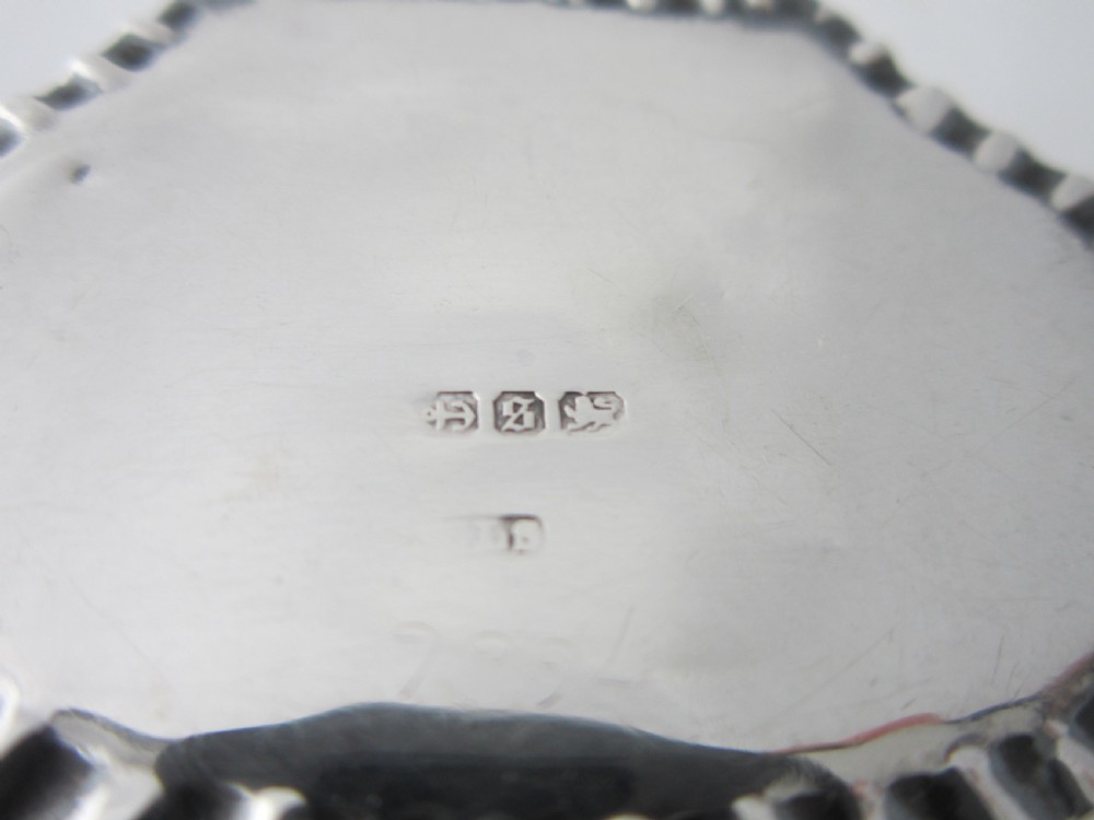 A small Victorian sterling silver pill box decorated with embossed scrollwork and a crimped frilled rim. View VII